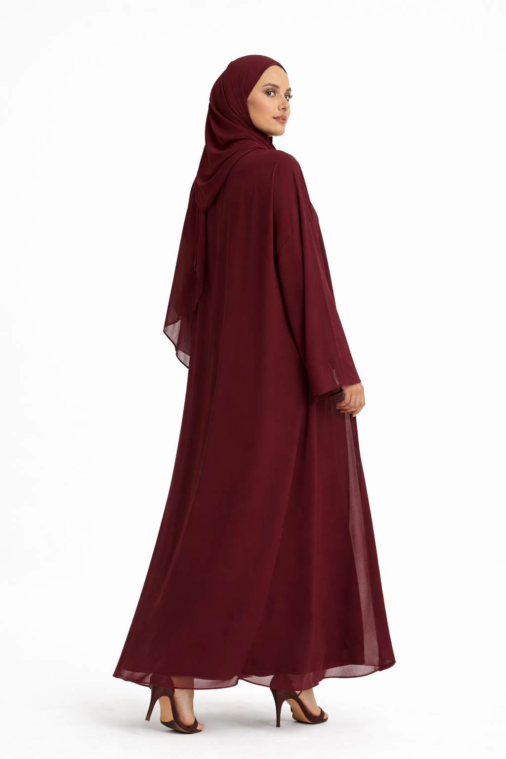 Woman wearing a long burgundy abaya with a hijab on a white background